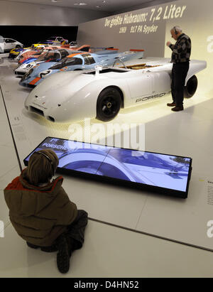 Visitors take a look at Porsche racing cars in the Porsche-Museum in Stuttgart, Germany, 31 January 2009. The museum in a futuristic building opened for the public for the first time on 31 January. Some 80 sports cars illustrate the company?s history. Photo: MARIJAN MURAT Stock Photo