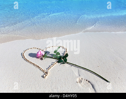 On a beach heart is drawn and the rose lies Stock Photo
