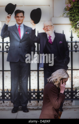 With smartphone in hand, a woman walks beneath a poster for the Charles Tyrwhitt menswear outfitters at Liverpool Street in the City of London, the capital's heart of its financial district - a good location for suits and businesswear. A pair of Englishmen raise their bowler hats in a gesture from a previous era, a bygone gentlemanly tradition. when hats said much of your social standing, a summary of your position in the class system. In the 21st century though, the hat is largely an item of clothing to wear only for extreme cold or heat. Stock Photo