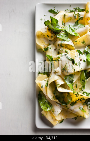 A plate of pappardelle pasta with creamy ricotta, baby spinach, fresh herbs and black pepper.