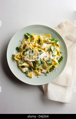 A plate of pappardelle pasta with creamy ricotta, baby spinach, fresh herbs and black pepper.