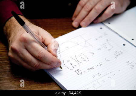 Close up of a man doing maths with a pen and paper, UK Stock Photo