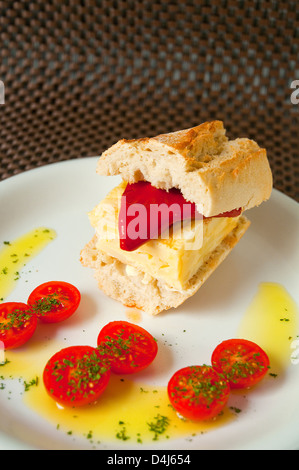 Spanish tapa: sandwich of Spanish omelet with Piquillo pepper, olive oil and cherry tomatoes. Close view. Stock Photo