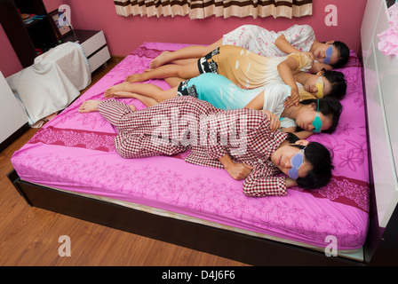 Asian Thai girls and boy sleep on one's side with eyes gel mask on bed on World Sleeping Day. Stock Photo