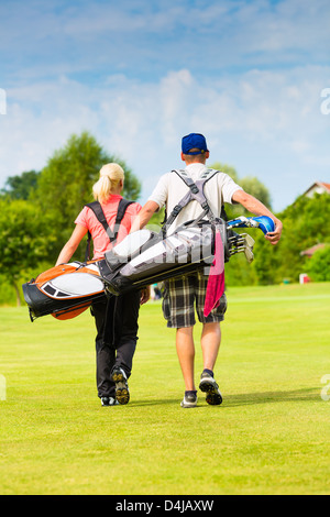 Young sportive couple playing golf on a golf course, they walking to the next hole Stock Photo