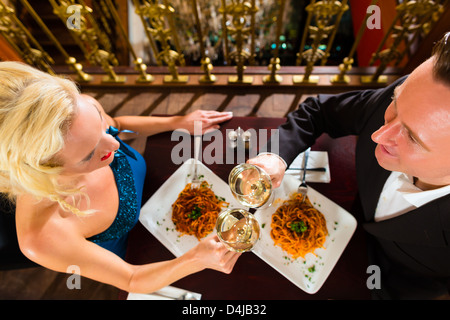 happy couple have a romantic date in a fine dining restaurant they drink wine and clinking glasses, cheers Stock Photo