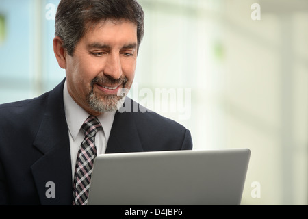Portrait of Hispanic businessman using laptop computer in office Stock Photo