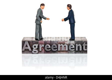 Hand painted businessmen figurines and the word Agreement in old metal letterpress isolated on a white background. Stock Photo