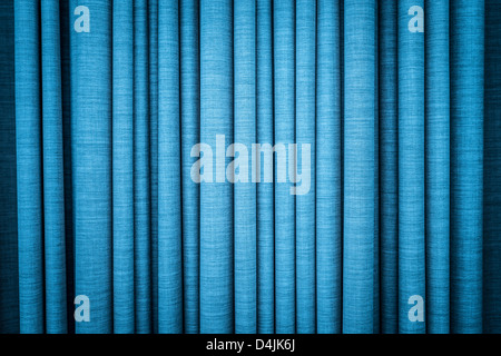 Close-up view of bright blue curtain in thin and thick vertical folds made of dense fabric. Textured abstract backgrounds and wa Stock Photo