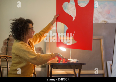 Artist cutting out red cardboard Stock Photo