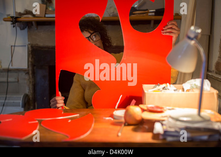 Artist cutting out red cardboard Stock Photo