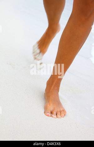 Woman’s running feet in white sand Stock Photo