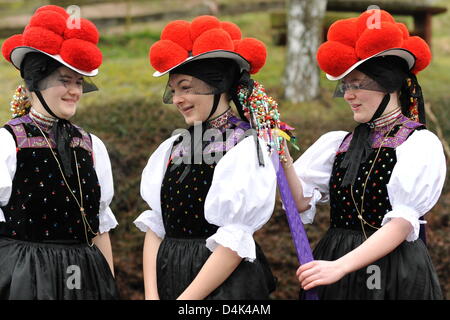 Saskia Keck (L-R), Anne Mueller and Luisa Wolber, candidates for confirmation, fix their traditional costume before they walk from the vicarage to the church in a pageant in Kirnbach in the Black Forest, Germany, 29 March 2009. Following an old tradition, all candidates for confirmation walk to the church in traditional costume in Kirnbach. On this occasion, the girls are allowed t Stock Photo