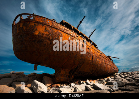 Rusted shipwreck on rocky beach Stock Photo