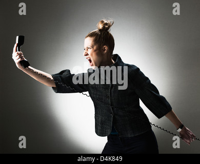 Businesswoman shouting at telephone Stock Photo