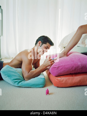 Man painting girlfriend’s toenails Stock Photo