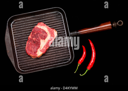 Meat in grill pan with chili peppers Stock Photo