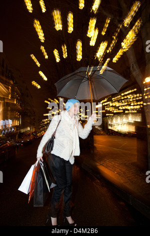 Woman under umbrella on city street Stock Photo