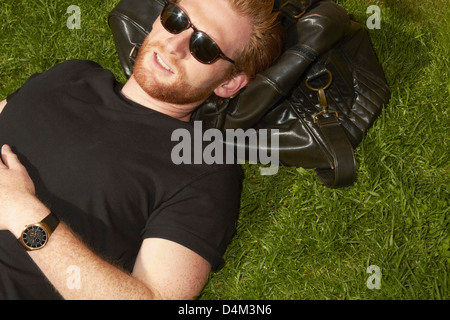 Man laying on bag in grass Stock Photo