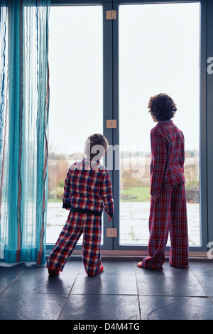 Boys in pajamas looking out window Stock Photo