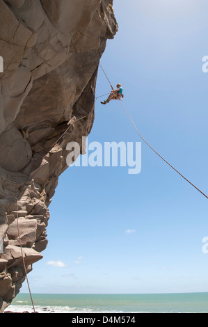 Rock climber abseiling jagged cliff Stock Photo