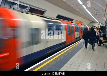 London Underground Central Line tube train departing train station people on platform with motion blur Shepherds Bush West London England UK Stock Photo