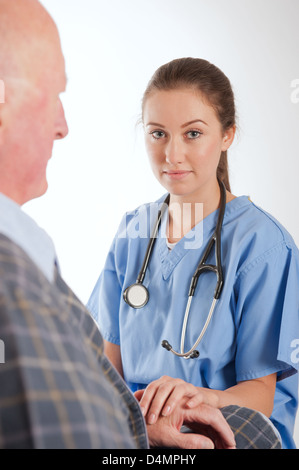 Elderly male patient being comforted by young female nurse/doctor. Stock Photo