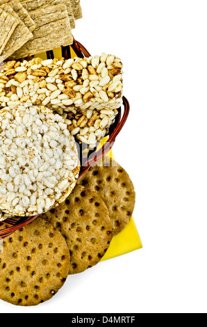 Round and rectangular cereal and rye crispbreads in a wicker basket on a yellow napkin isolated on white background Stock Photo