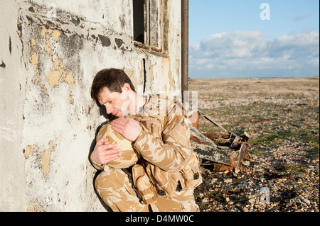 Soldier suffering with Post Traumatic Stress Disorder on the battlefield. Soldier is wearing British military desert uniform. Stock Photo