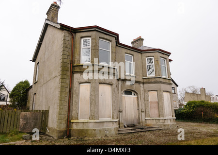 Abandoned house has windows and doors boarded up.  The building has been condemned as will shortly be demolished. Stock Photo