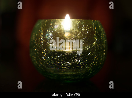 A lit tealight candle in a glass holder Stock Photo