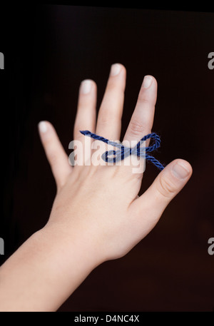 Close-up of a blue bow knot on a child's finger. Selective focus on knot. Stock Photo