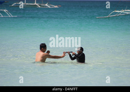 Father-son duo playing in the blue sea Stock Photo