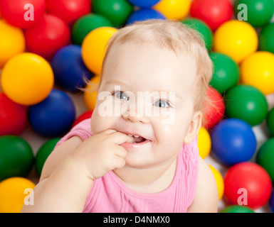 Portrait of a smiling infant sitting among colorful balls Stock Photo