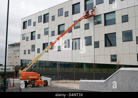 Man cleaning a modern building using a JLG  Telescopic Boom Lift type 660SJ cherry picker Newcastle north east England UK Stock Photo