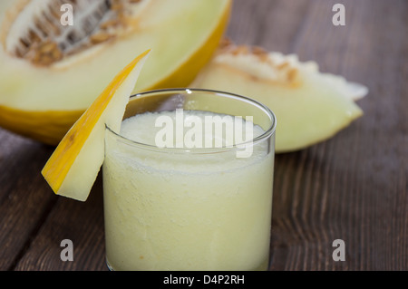 Fresh made Honeydew Juice with fruit pieces on wooden background Stock Photo