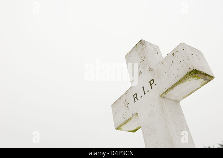 Low angle view of cross shaped headstone with R.I.P. written on it. Stock Photo