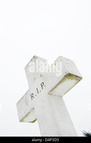 Low angle view of cross shaped headstone with R.I.P. written on it. Stock Photo