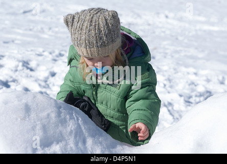 Child toddler baby blond girl walking and playing in snowy landscape - winter mountain Stock Photo