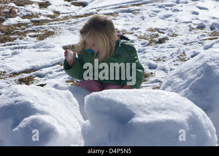 Child toddler baby blond girl walking and playing in snowy landscape - winter mountain Stock Photo