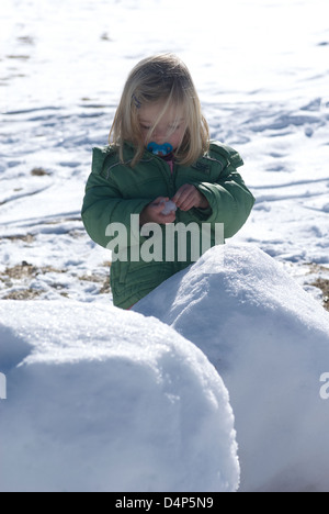 Child toddler baby blond girl walking and playing in snowy landscape - winter mountain Stock Photo