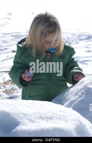 Child toddler baby blond girl walking and playing in snowy landscape - winter mountain Stock Photo