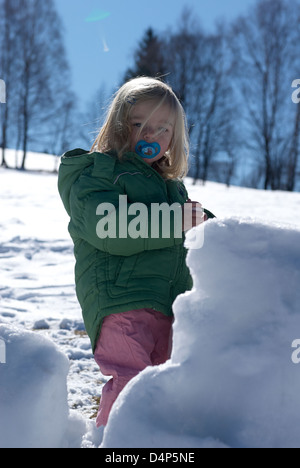 Child toddler baby blond girl walking and playing in snowy landscape - winter mountain Stock Photo