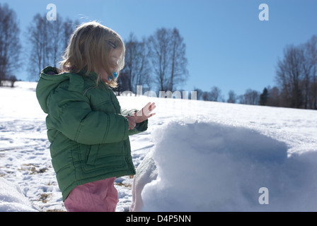 Child toddler baby blond girl walking and playing in snowy landscape - winter mountain Stock Photo