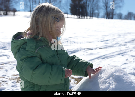 Child toddler baby blond girl walking and playing in snowy landscape - winter mountain Stock Photo