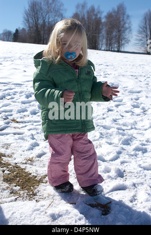 Child toddler baby blond girl walking and playing in snowy landscape - winter mountain Stock Photo