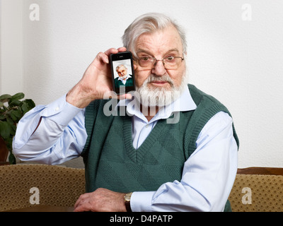Senior man holding smart phone and showing his picture Stock Photo