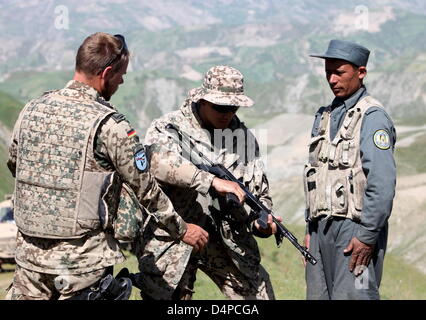 German Bundeswehr soldiers of the MOLT 3 unit look at the AK47 machine gun of an Afghan policeman during a patrol in the province Badakhshan, Afghanistan, 27 May 2009. MOLT 3 is a ?Mobile Observation and Liaison Team? of the German ?Provincial Reconstruction Team? in Feyzabad and is on a three-day patrol in the region. Photo: Marcel Mettelsiefen Stock Photo