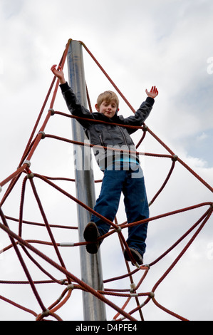 Young 10 year old Caucasian boy on a rope climbing frame in park in Bristol, UK Stock Photo