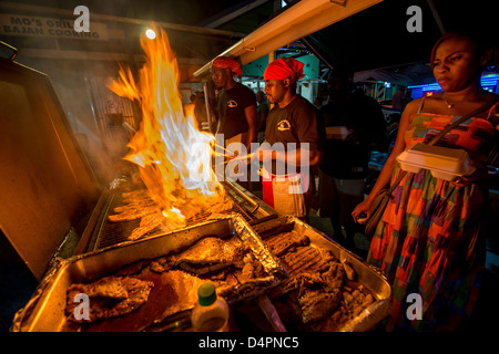 Cooks frying up fish on a BBQ at Oistins fish fry night, Oistins, parish of Christ Church, Barbados , Caribbean, West Indies Stock Photo